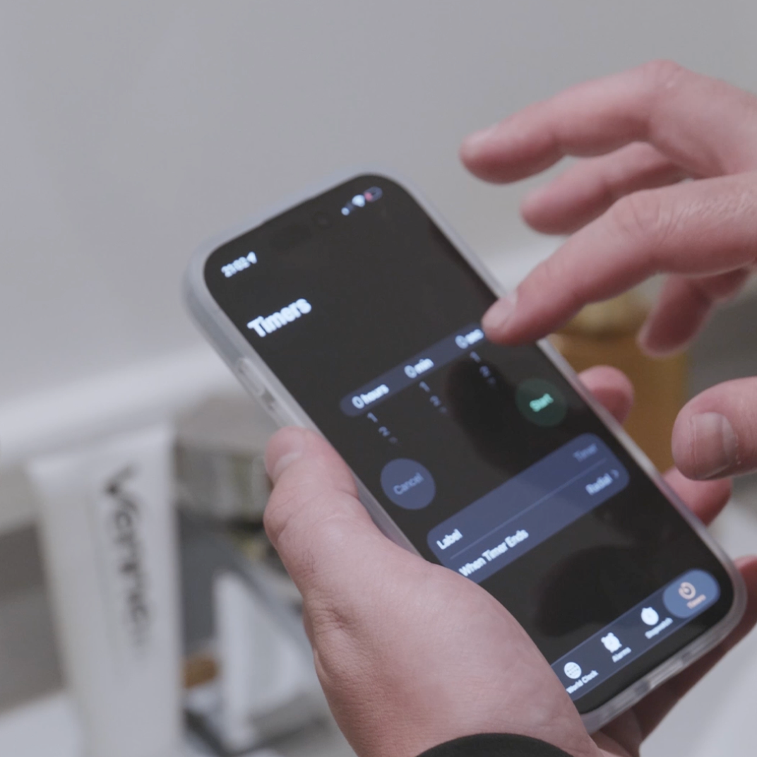 Person holding a smartphone with a timer app interface on a blurred background