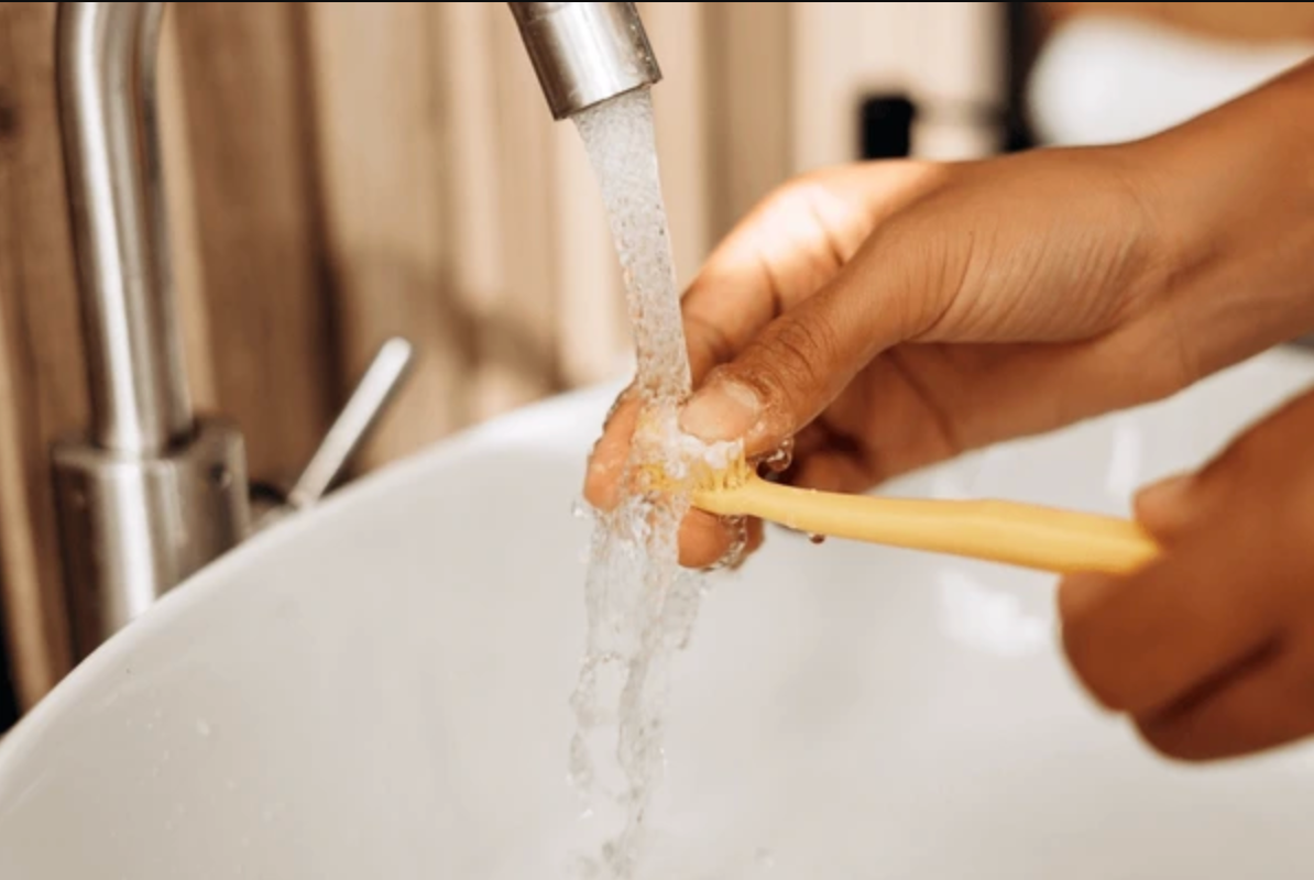 Hand washing toothbrush at a white sink