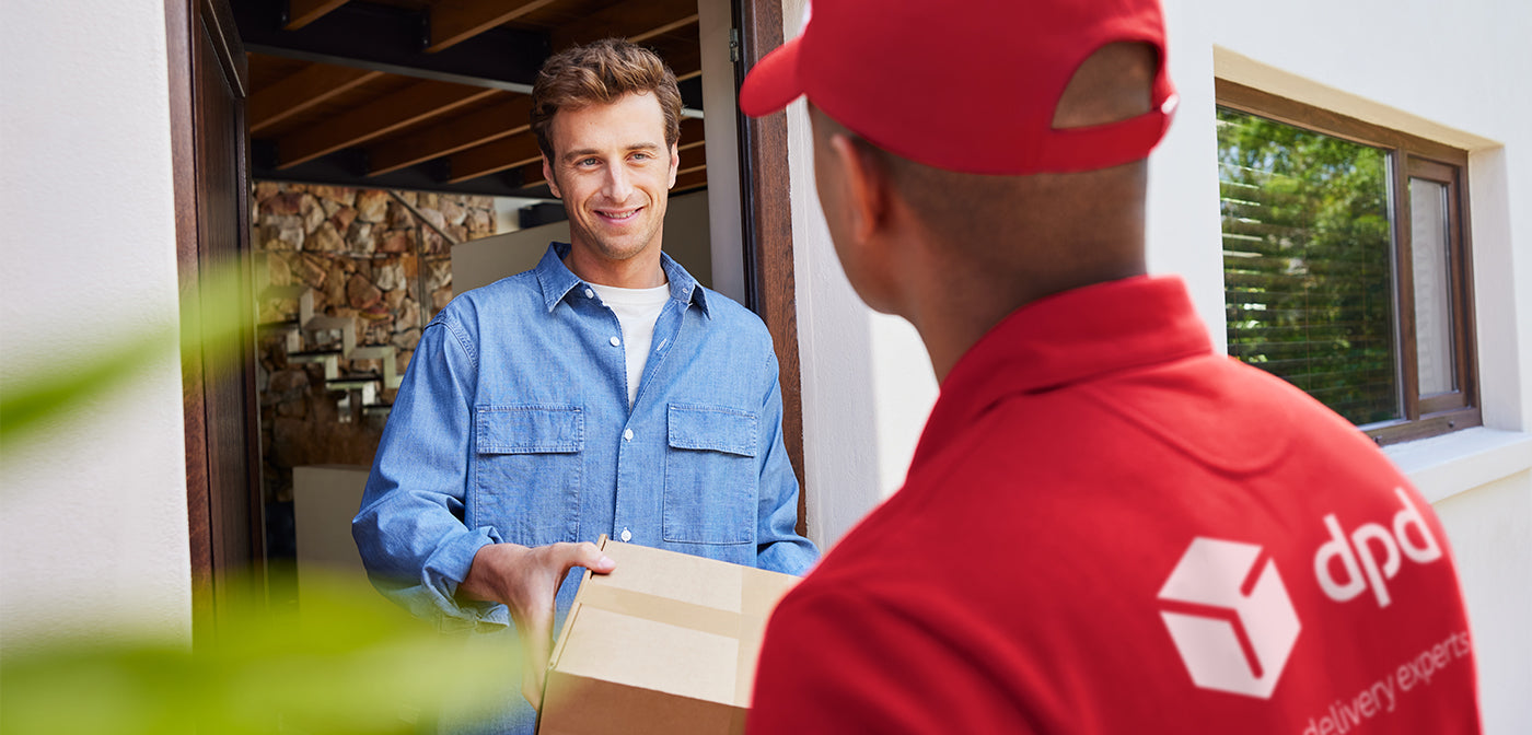 Man receiving a package from a delivery person wearing a red DPD uniform.