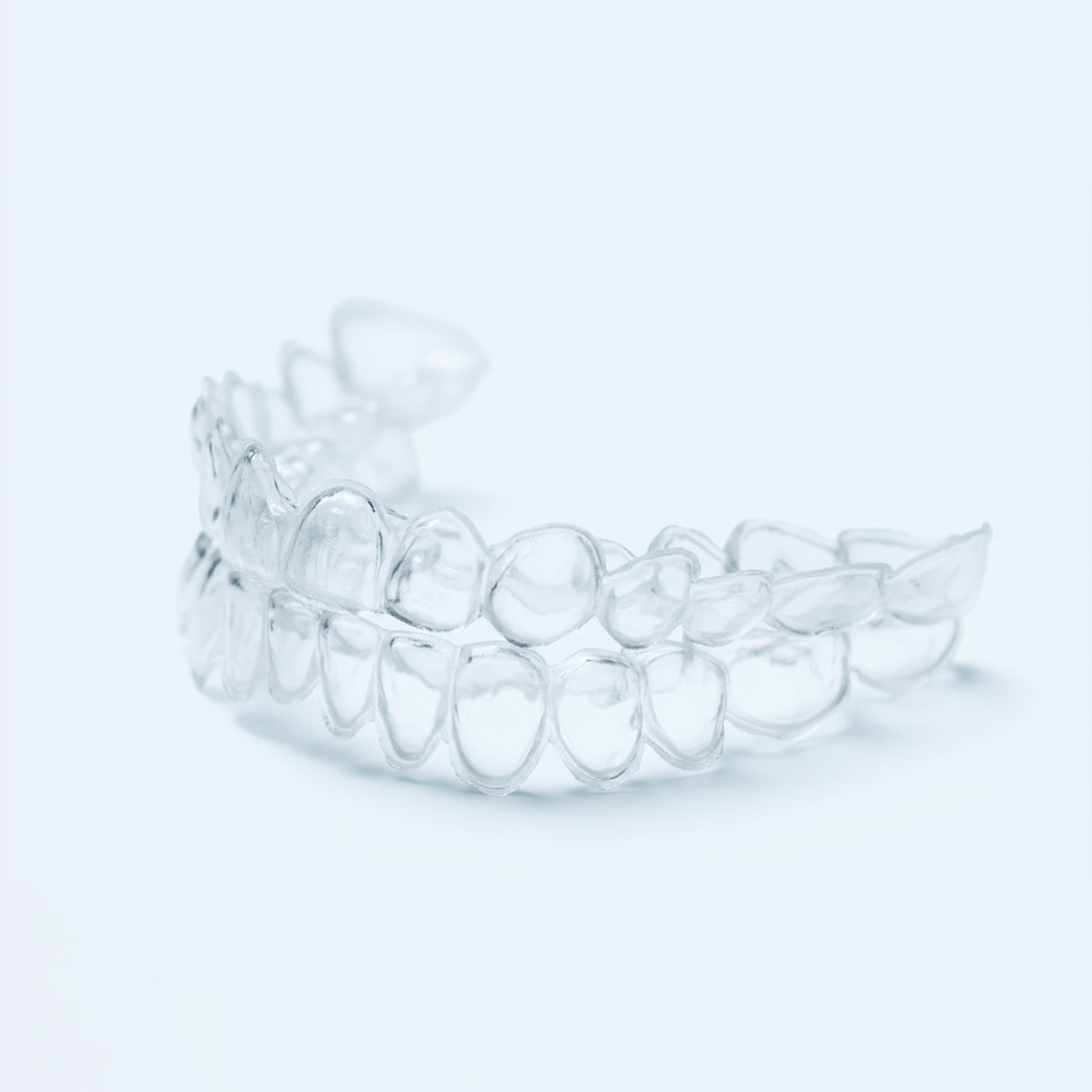Clear professional teeth whitening trays with dosing dots on light blue background