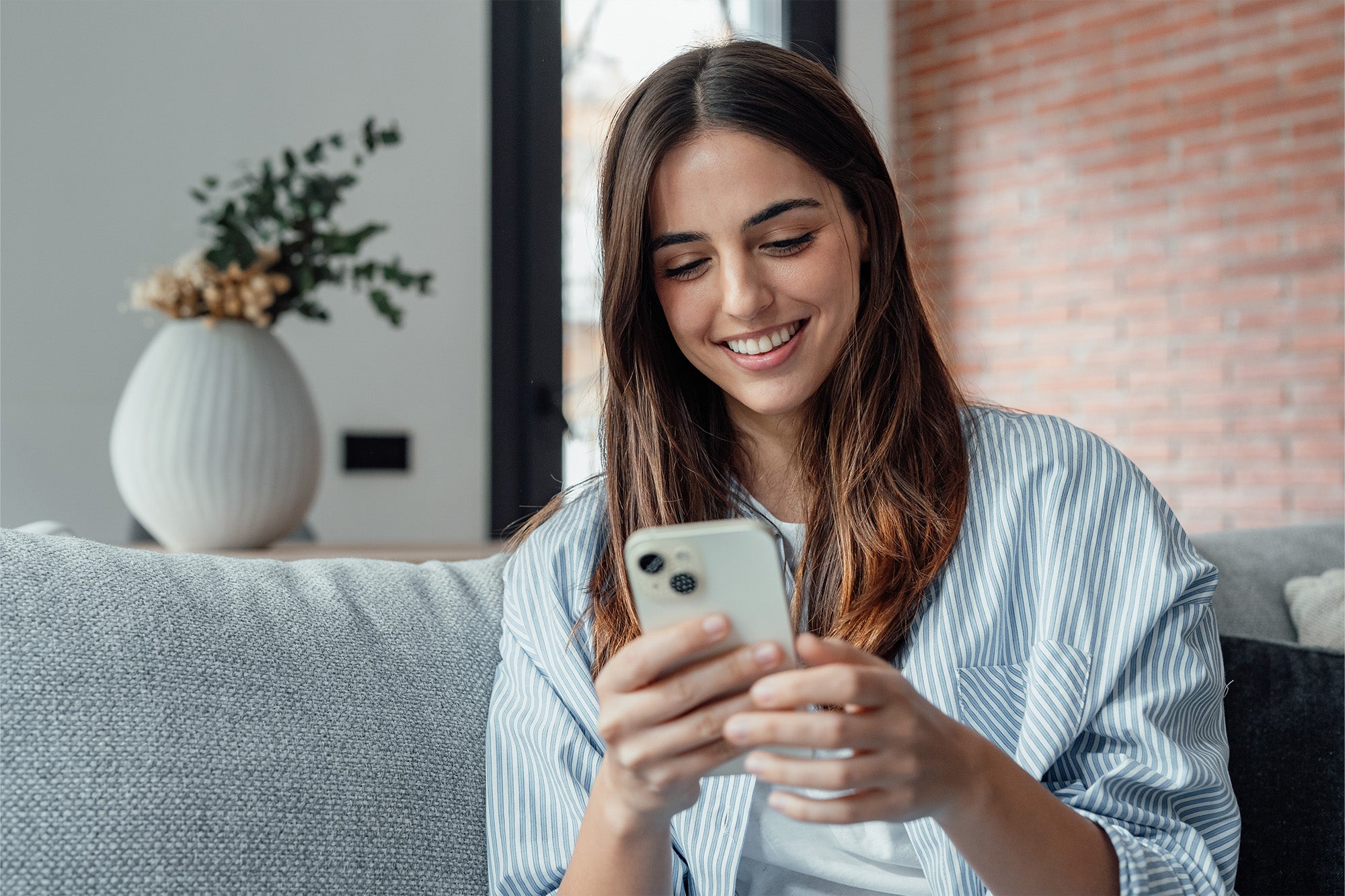 Woman using a smartphone in a cozy living room.