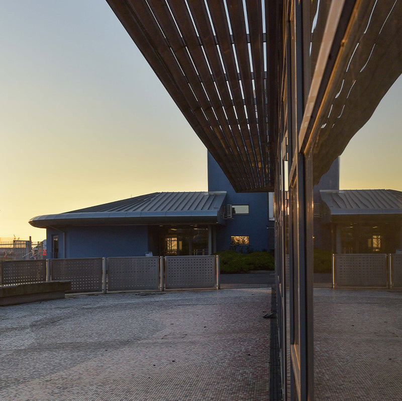 Modern building with a flat roof and reflective glass facade at sunset.