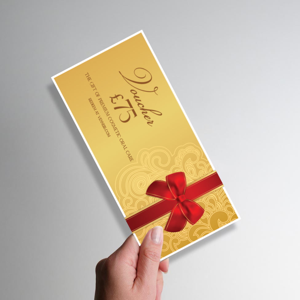 Gold voucher with red ribbon held by a hand on a gray background
