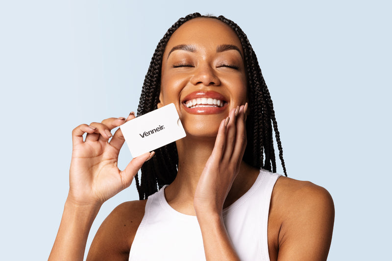 Woman holding dental tape with Venneir branding and light blue background