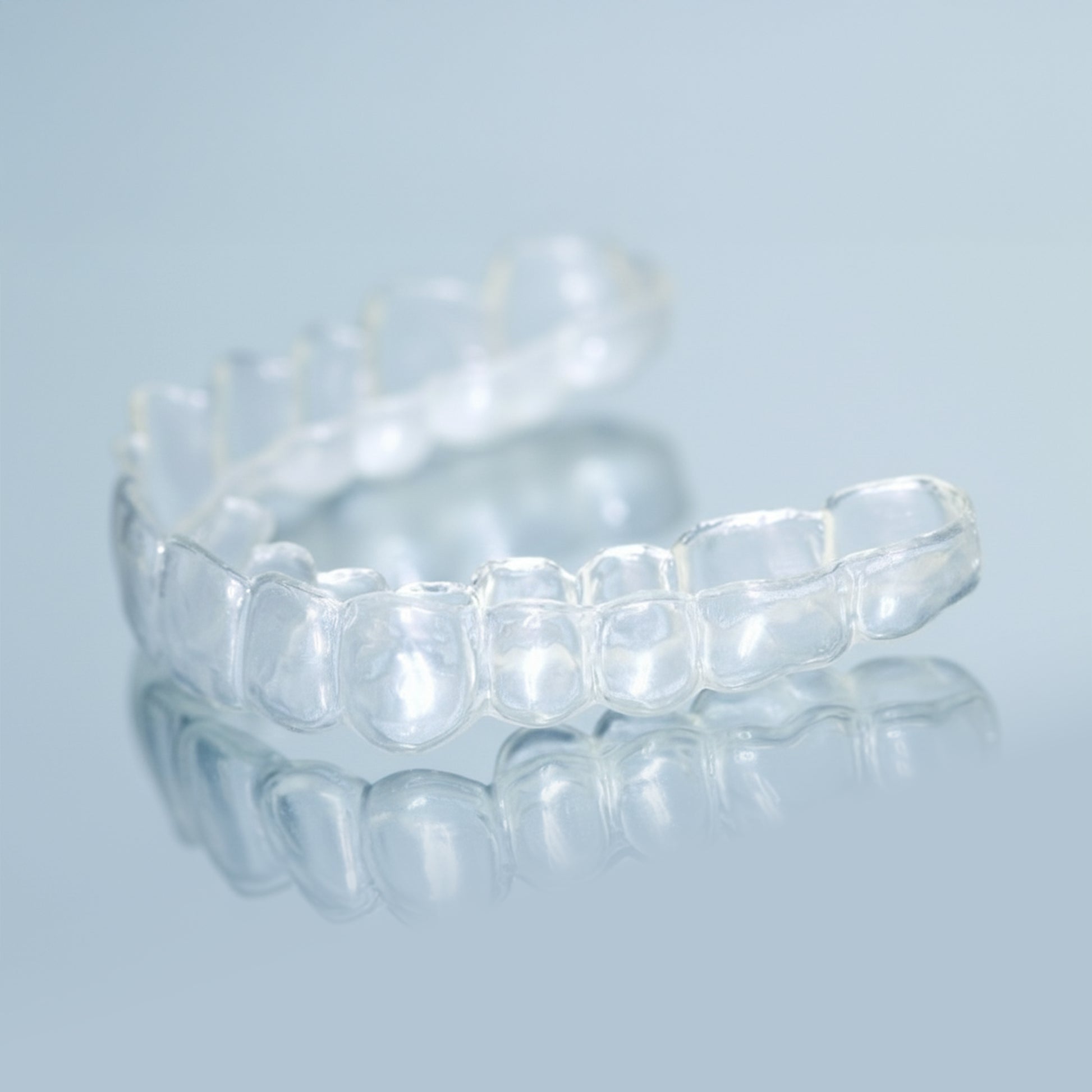 Clear professional teeth whitening trays with dosing dots on light blue background