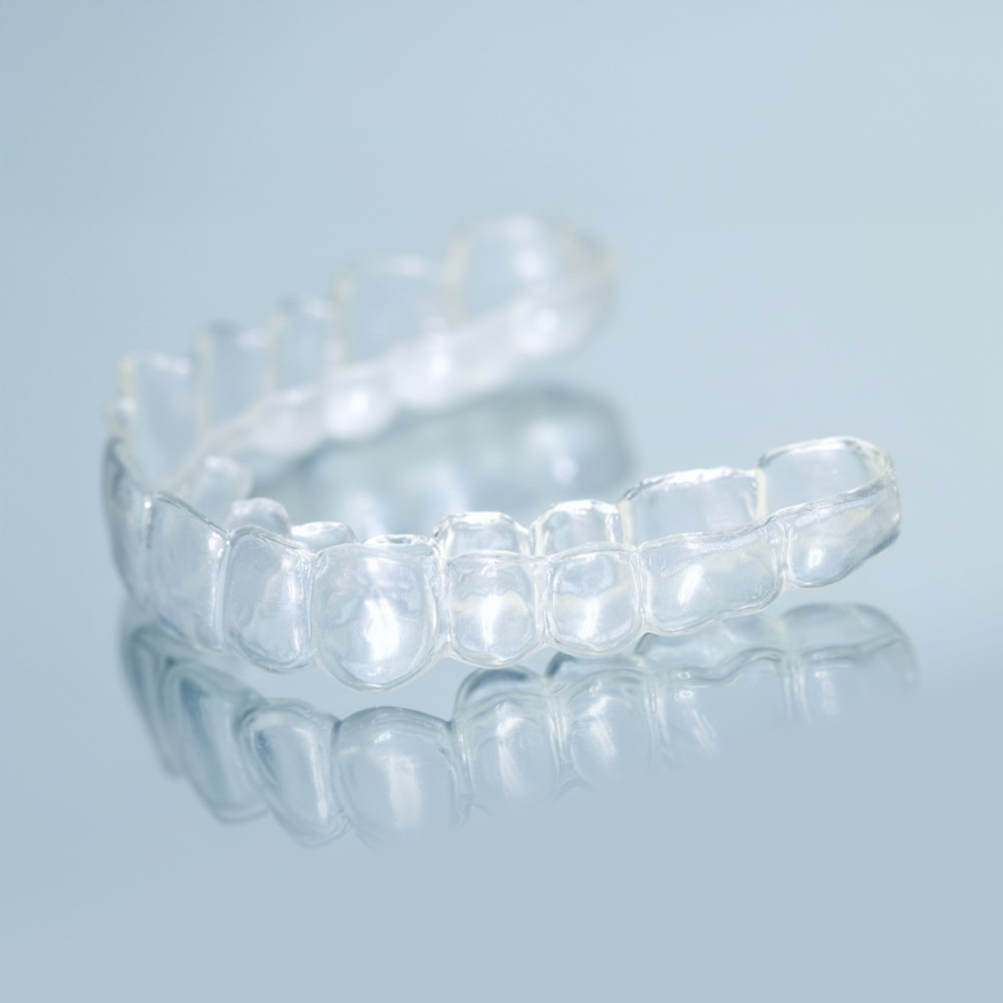 Clear professional teeth whitening trays with dosing dots on light blue background