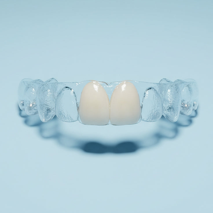 Clear dental pontic essix retainer with teeth on a light blue background