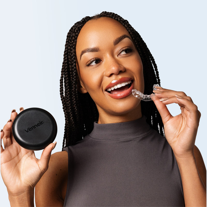 Woman holding a clear aligner and a black case with 'Venneir' branding on a light blue background