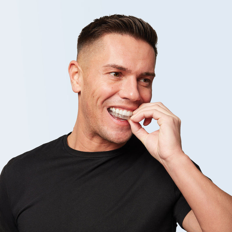 Man holding retainer wearing a black shirt against a light background
