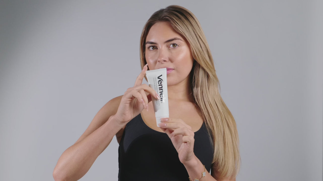 Woman opening 'Venneir' toothpaste on plain background