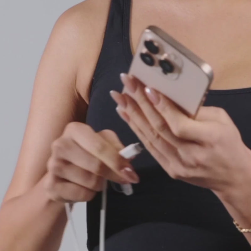 woman plugging led whitening light in to phone and wearing