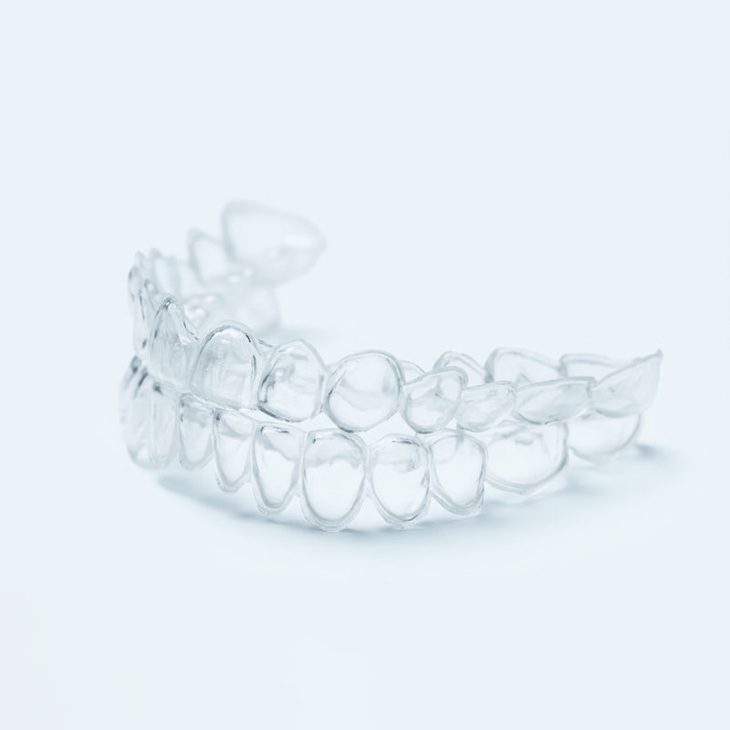 Clear professional teeth whitening trays with dosing dots on light blue background